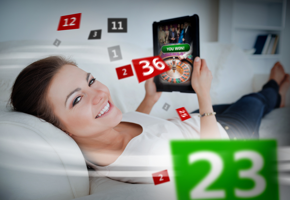 Woman lying on couch and gambling on tablet